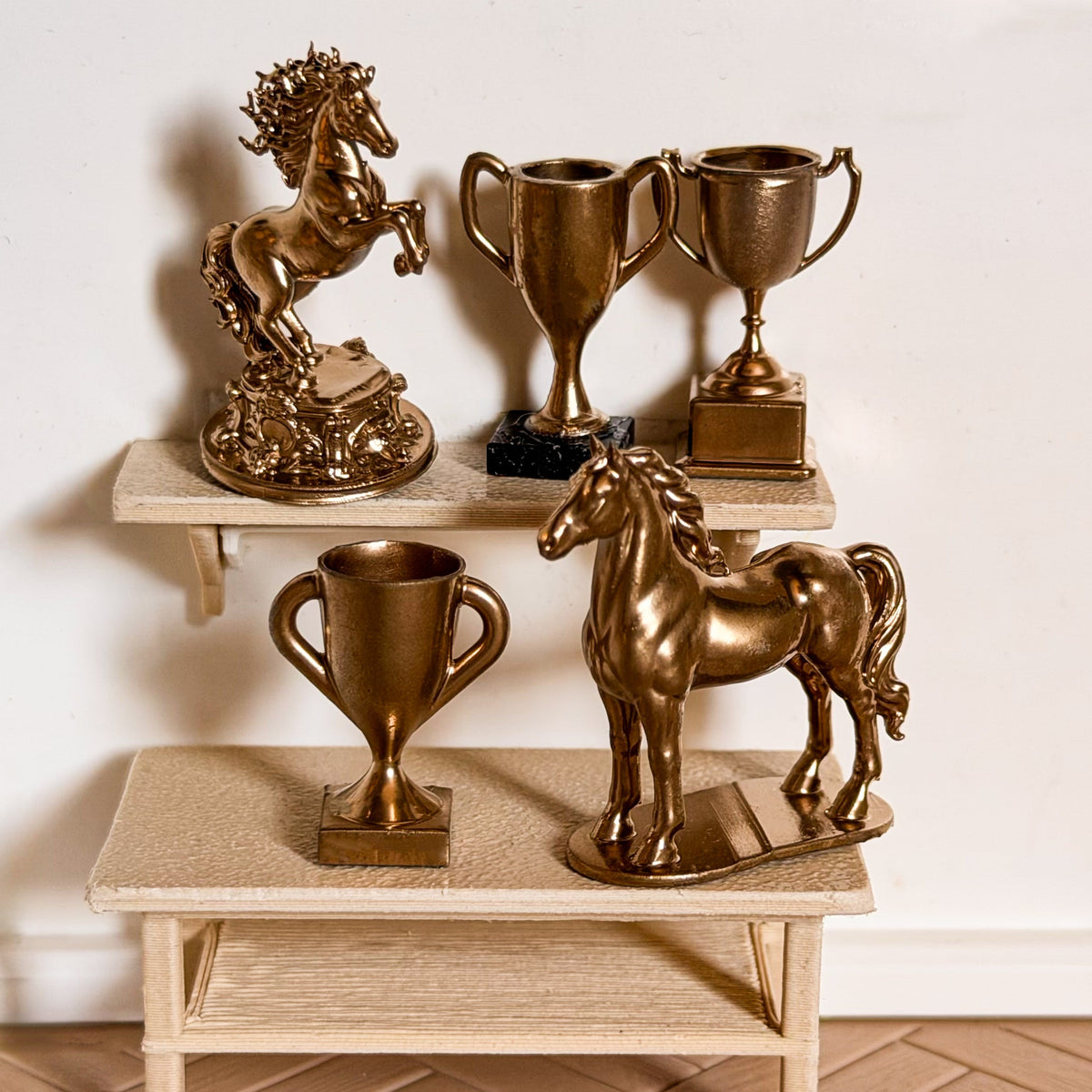 Gold horse trophy set: a rearing horse statue, a standing horse statue and three trophy cups on a miniature shelf and table for Schleich model horses