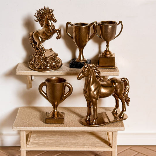 Gold horse trophy set: a rearing horse statue, a standing horse statue and three trophy cups on a miniature shelf and table for Schleich model horses