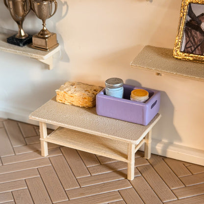 Miniature light oak table with a lower shelf holding a lavender grooming box, two jars and a sponge, under wall shelves with trophies and a framed horse picture