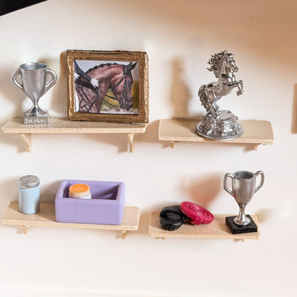 Four miniature wall shelves displaying a silver trophy, a framed horse picture, a silver rearing horse statue and a lavender grooming box with accessories